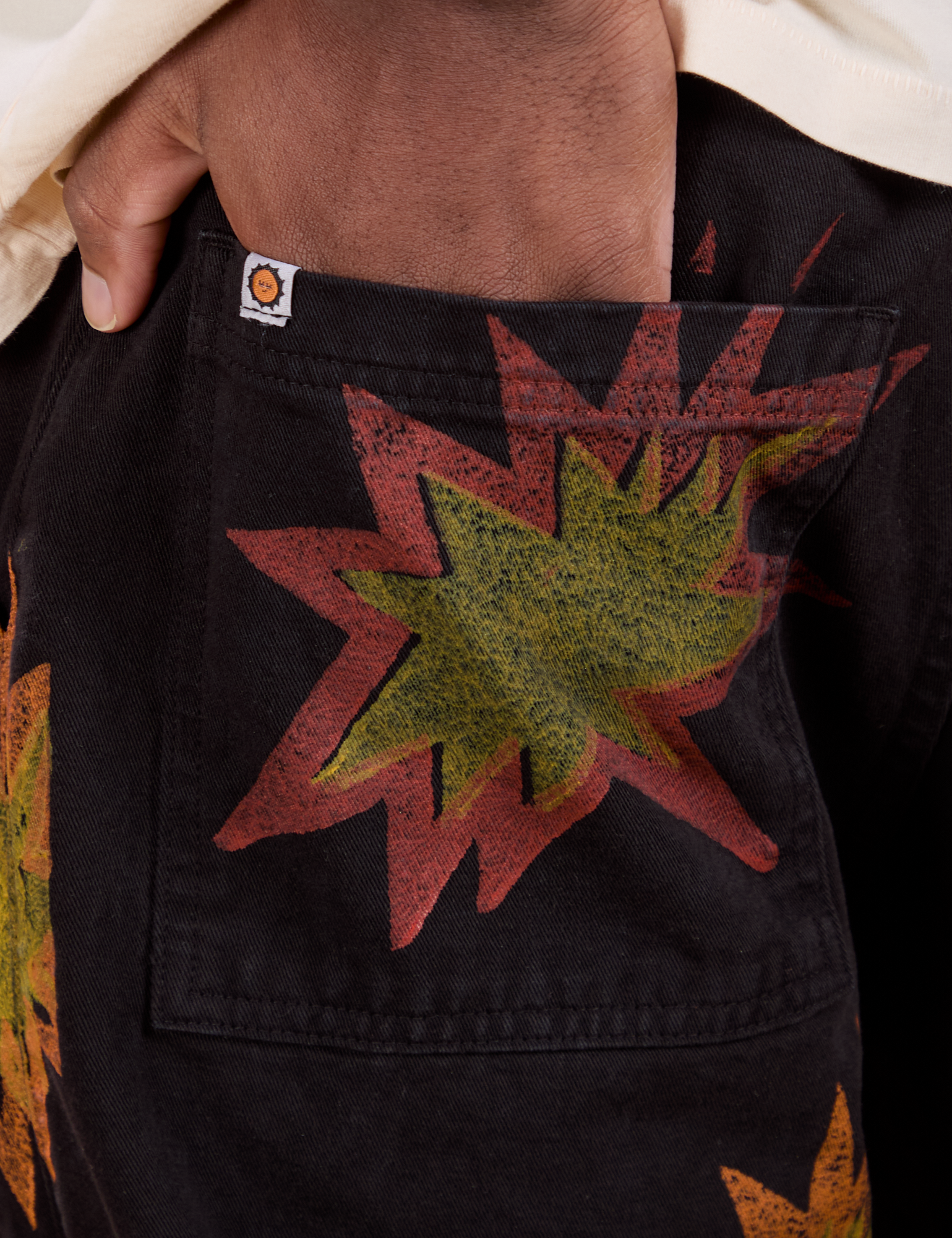 Close up of Isaac&#39;s hand in the back pocket of Paintstamped Work Pants in Explosion