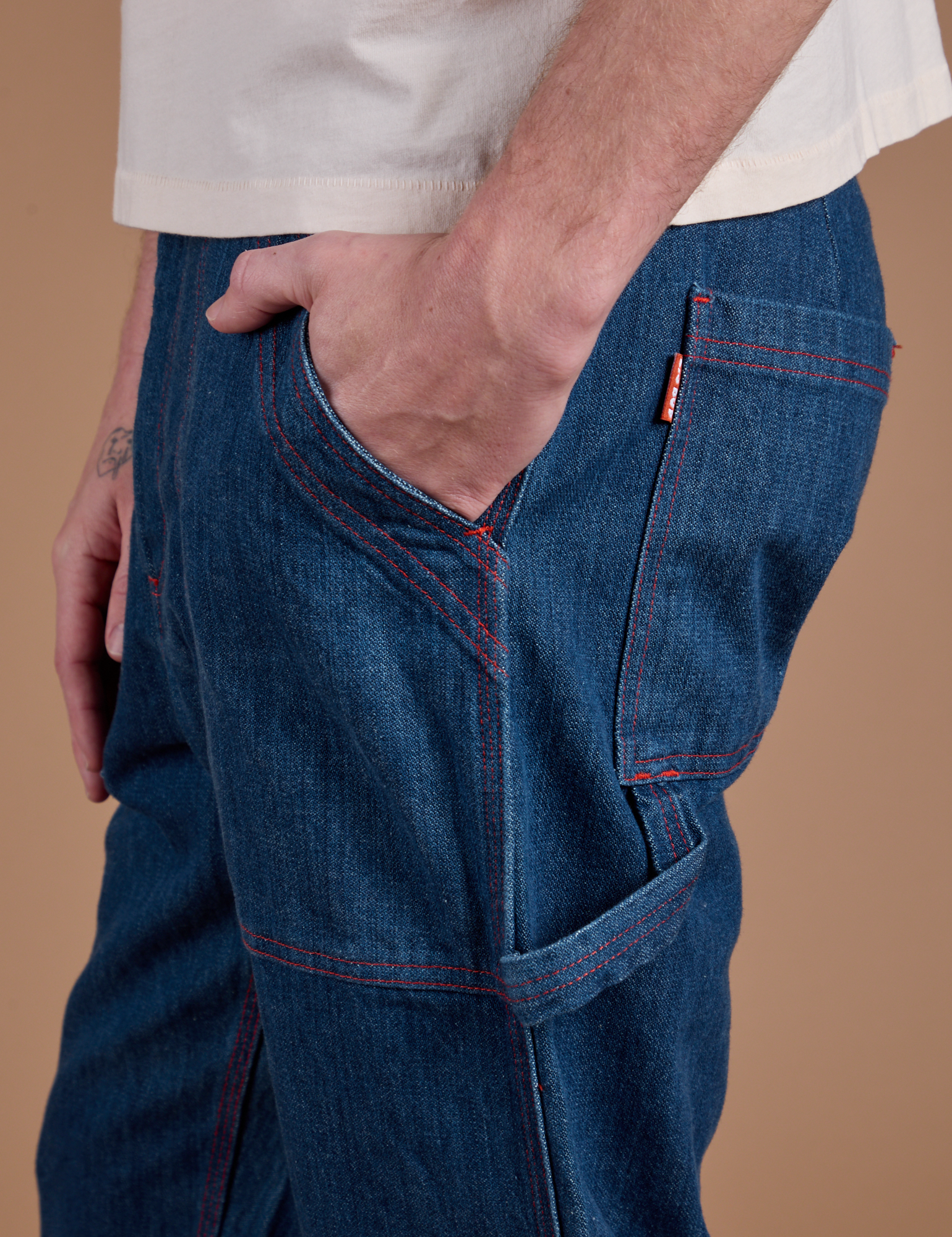 Close up of Quinn's hand in the front pocket of Carpenter Jeans in Dark Wash