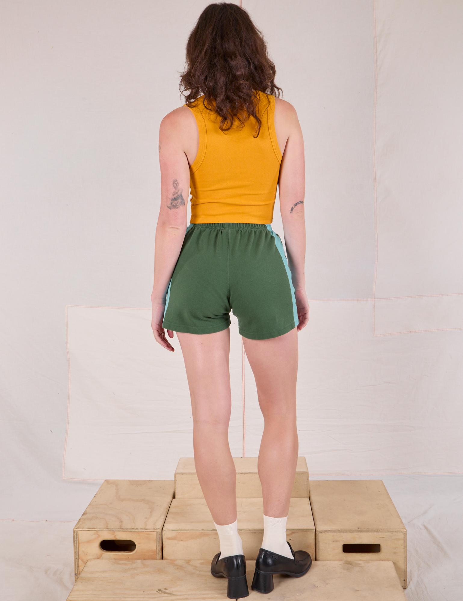 Back view of Painted Stripe Easy Shorts in Dark Emerald Green and golden yellow Cropped Tank on Alex