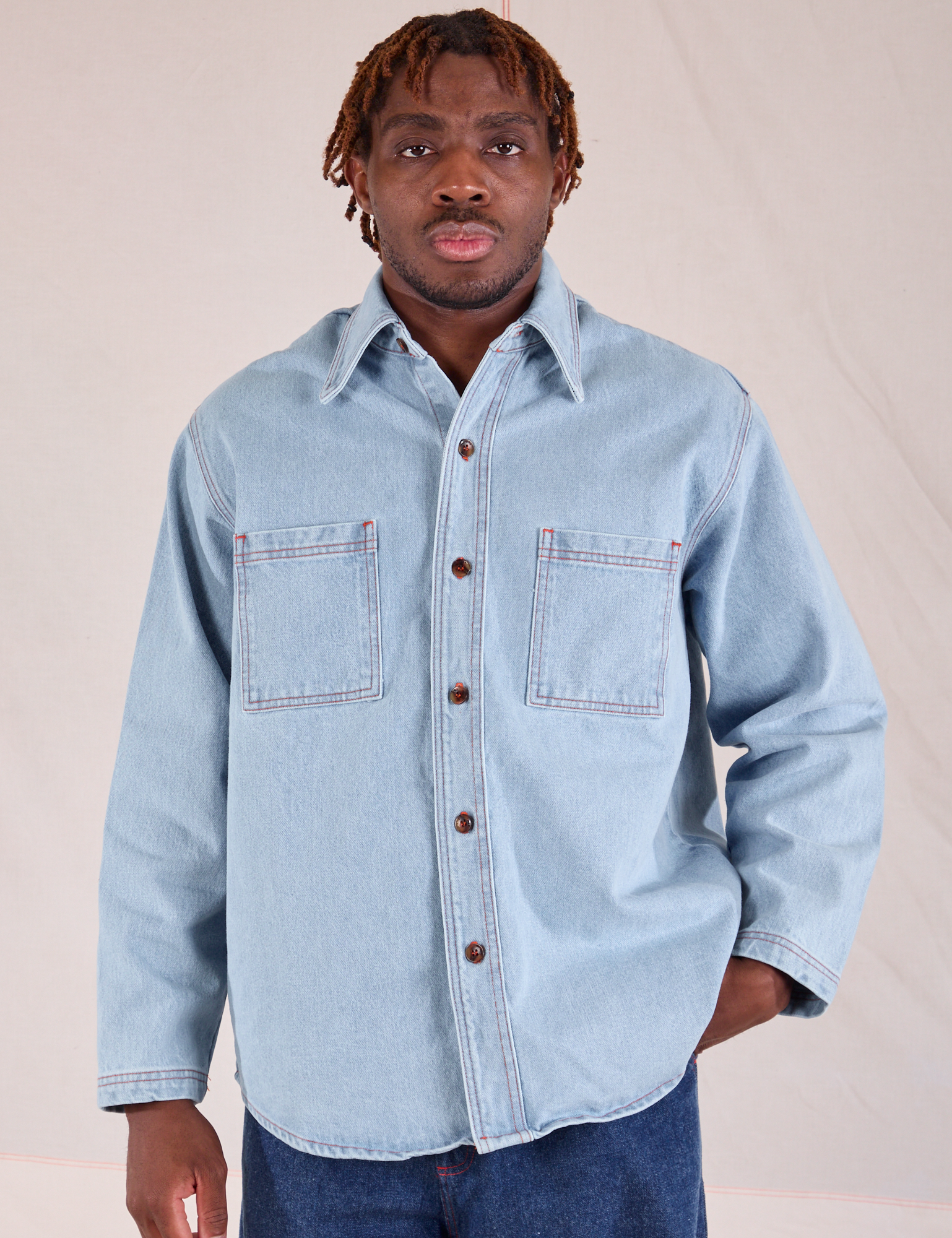 Issac is wearing a buttoned up Denim Overshirt in Light Wash