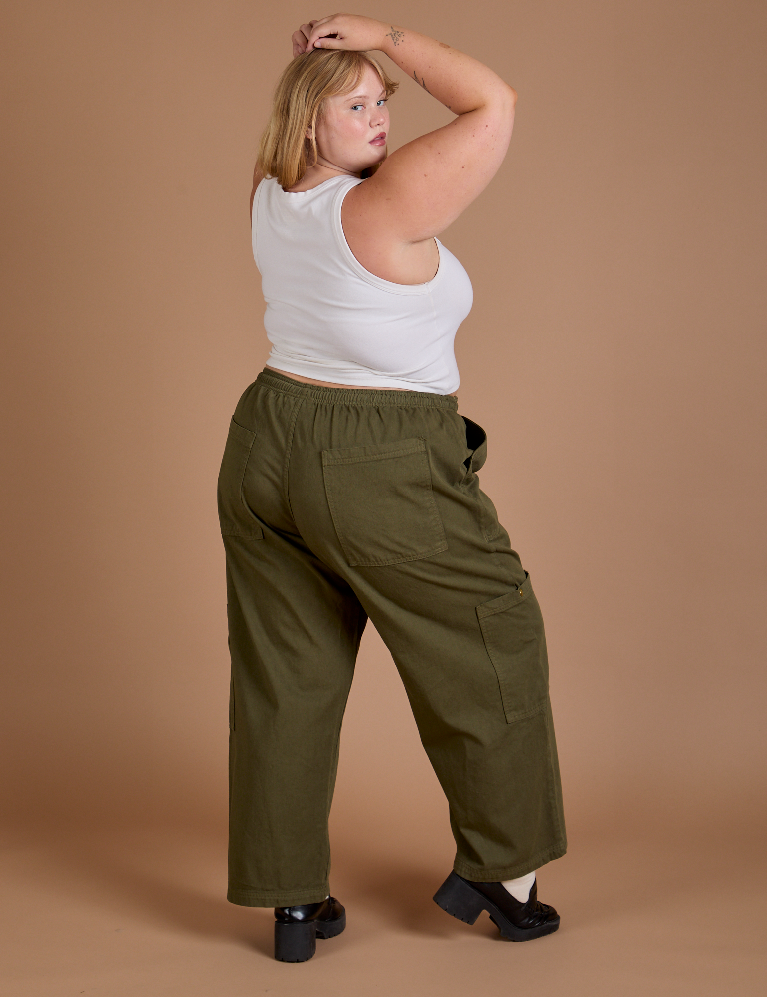 Angled back view of Drop Pocket Cargo Pants in Surplus Green and Cropped Tank in Vintage Tee White