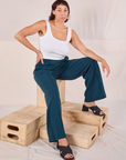 Tiara is wearing Easy Western Pants in Lagoon and sitting on a wooden crate