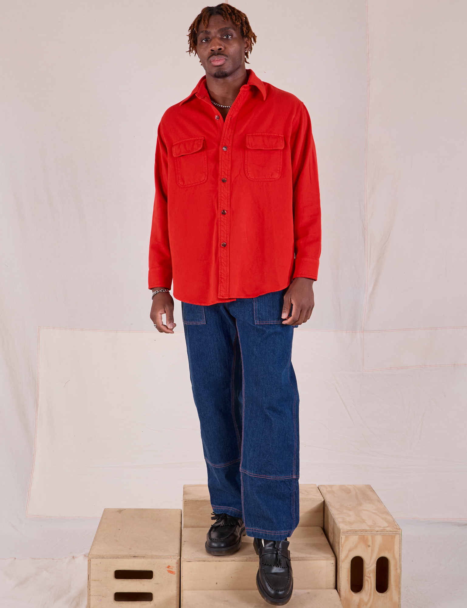 Isaac is wearing Flannel Overshirt in Mustang Red paired with dark wash Carpenter Jeans