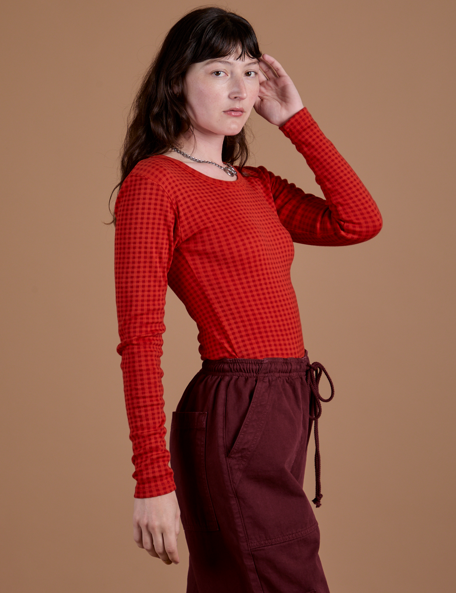 Angled front view of Gingham Long Sleeve Baby Tee in Mustang Red on Alex