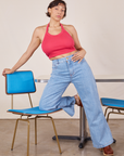 Tiara is wearing a Halter Top in Hot Pink. She has her left knee on a vintage blue chair and the right foot touching the ground.