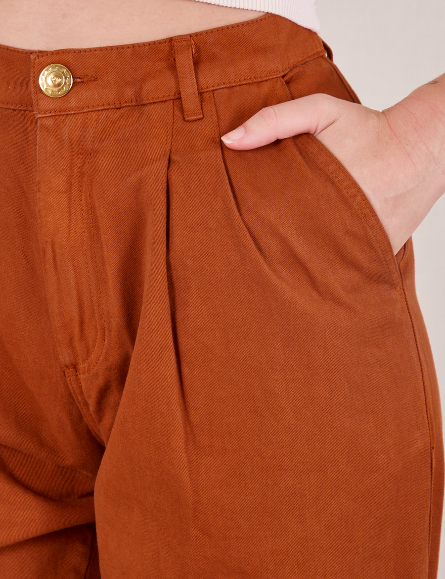 Front pocket close up of Heavyweight Trousers in Burnt Terracotta. Alex has her hand in the pocket.