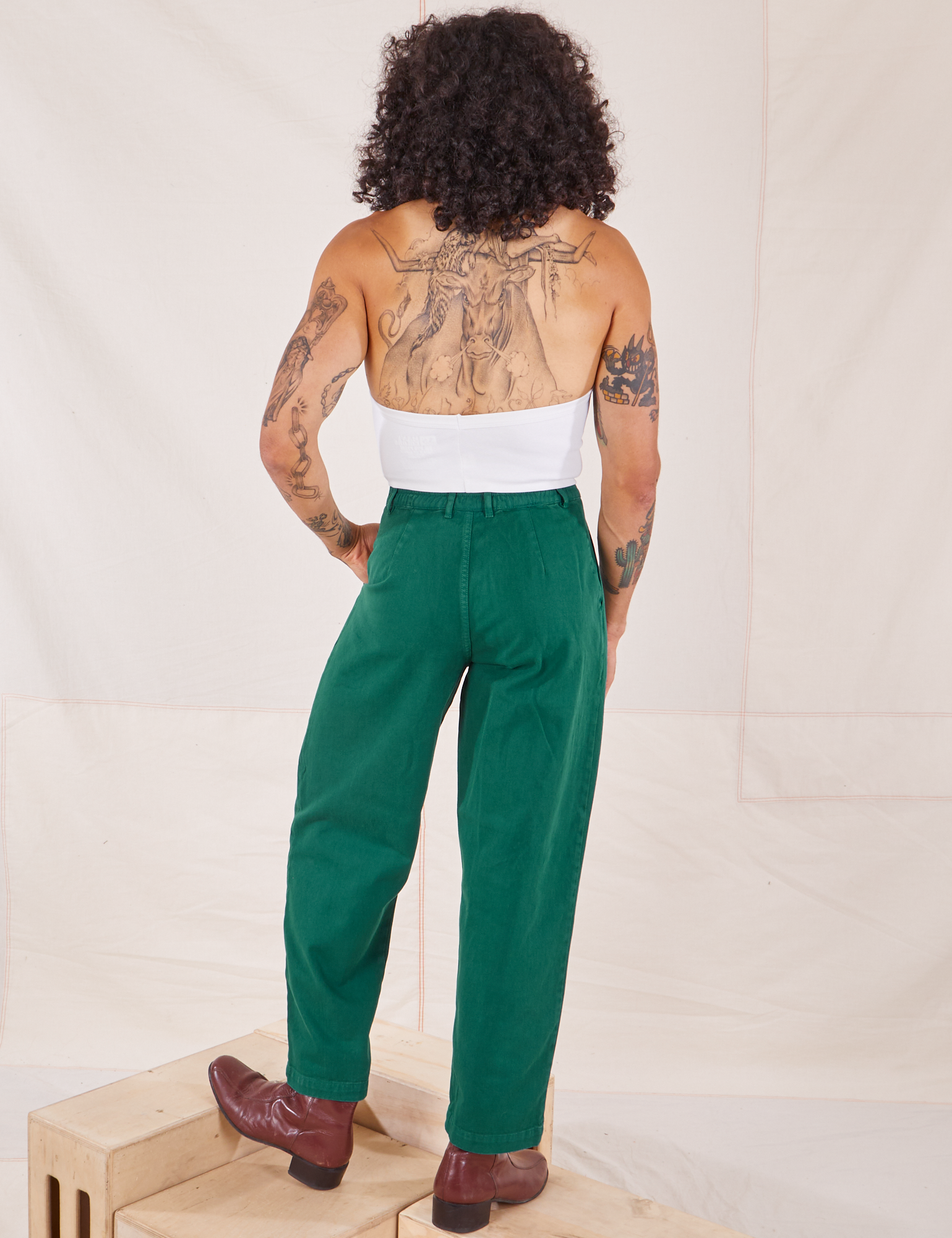 Back view of Heavyweight Trousers in Hunter Green and vintage off-white Halter Top worn by Jesse