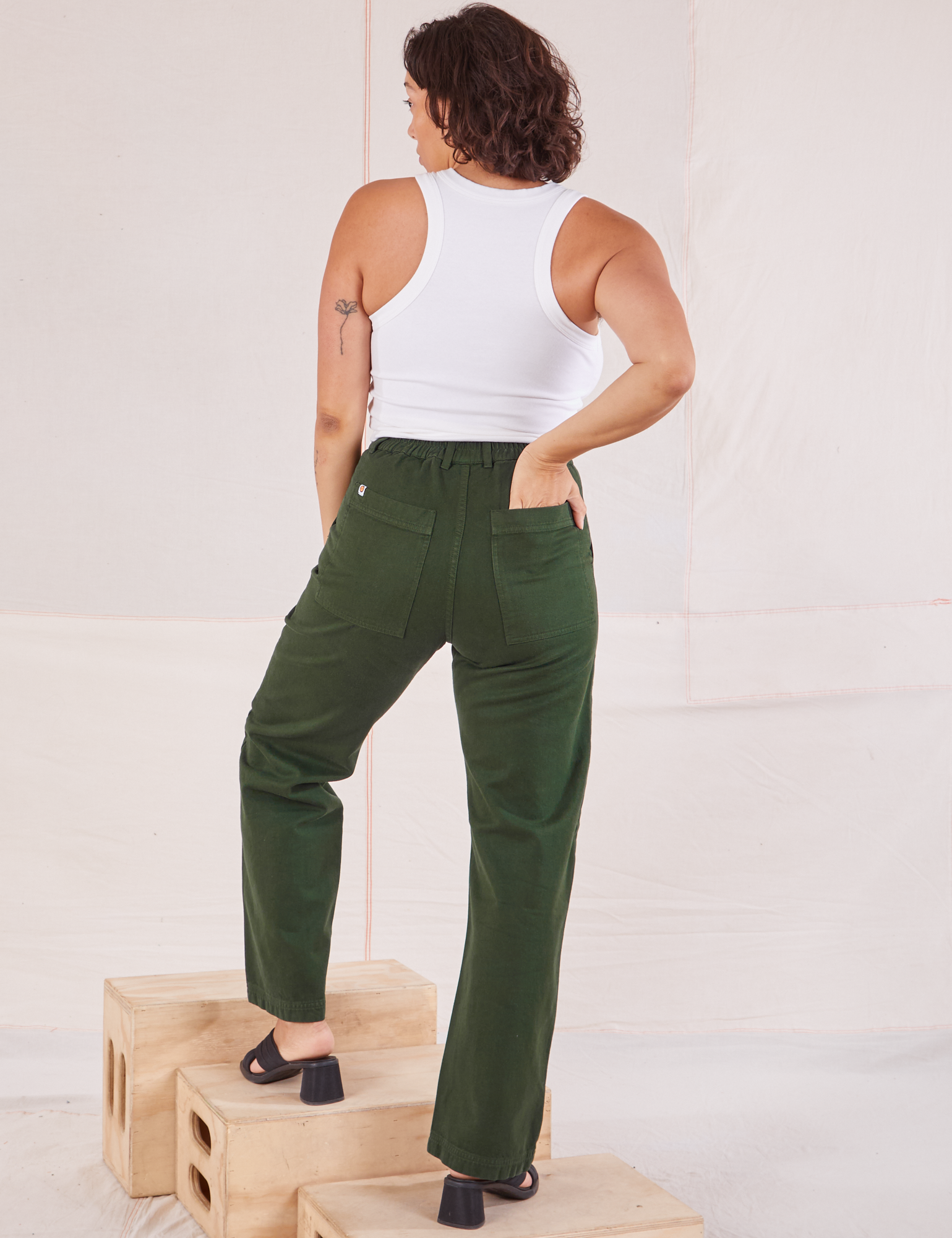 Back view of Organic Work Pants in Swamp Green and Racerback Tank in vintage tee off-white