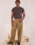 Issac is 5'10" and wearing M Mid-Rise Pleated Trousers in Desert Brown paired with espresso brown Organic Vintage Tee