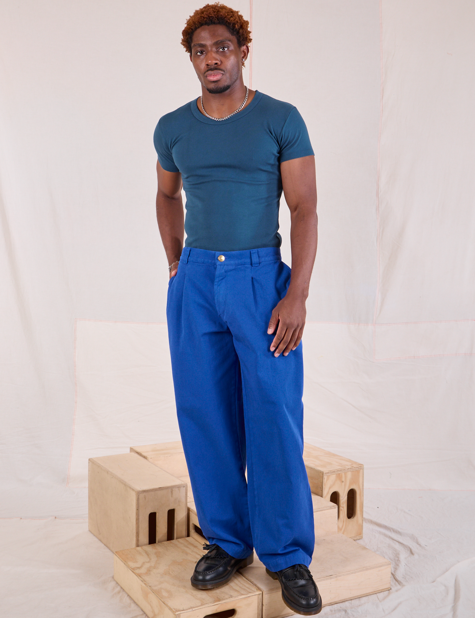 Issac is 5&#39;10&quot; and wearing M Mid-Rise Pleated Trousers in Royal Blue paired with lagoon Baby Tee