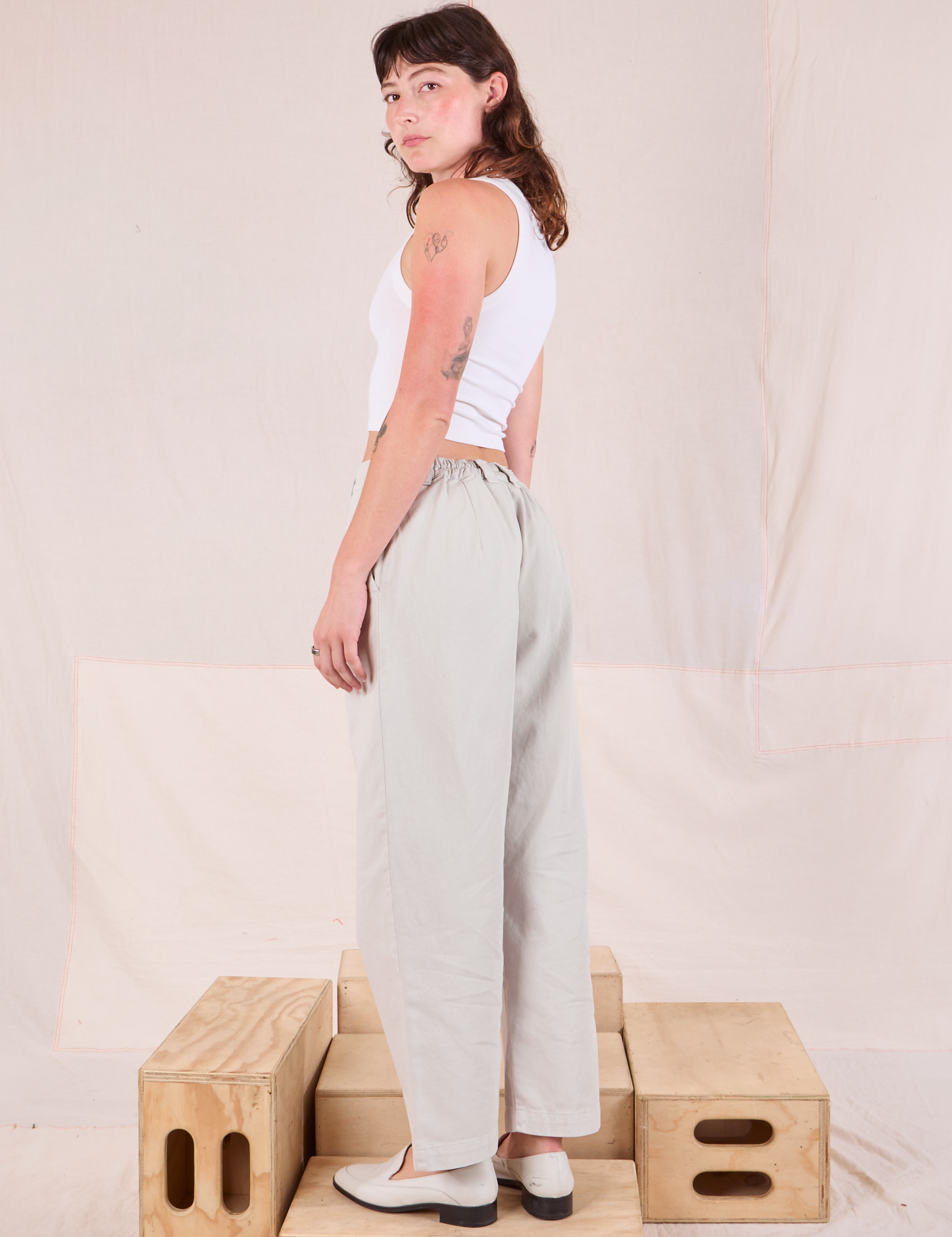 Angled back view of Mid-Rise Pleated Trousers in Stone White on Alex