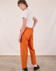 Angled back view of Work Pants in Construction Orange and Burly Tee in Vintage Tee Off-White