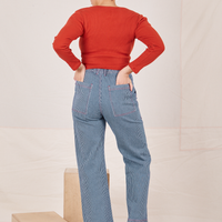 Back view of Railroad Stripe Denim Work Pants and paprika Long Sleeve V-Neck Tee worn by Tiara. She has both hands in the back pocket.