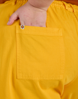 Close up of Juliet's hand in the back pocket of Longline Work Shorts in Sunshine Yellow