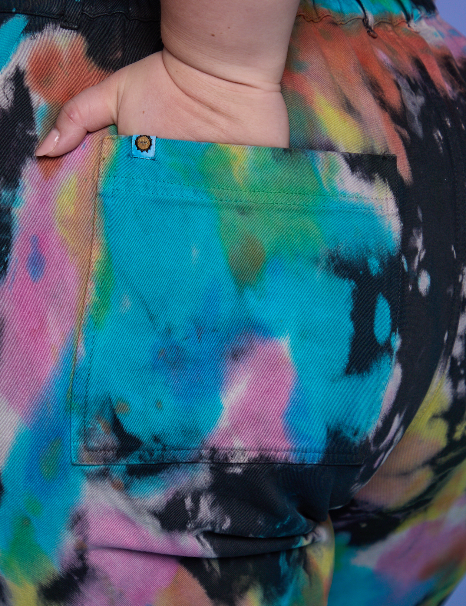 Close up of Ashley&#39;s hand in the back pocket of Short Sleeve Jumpsuit in Rainbow Magic Waters