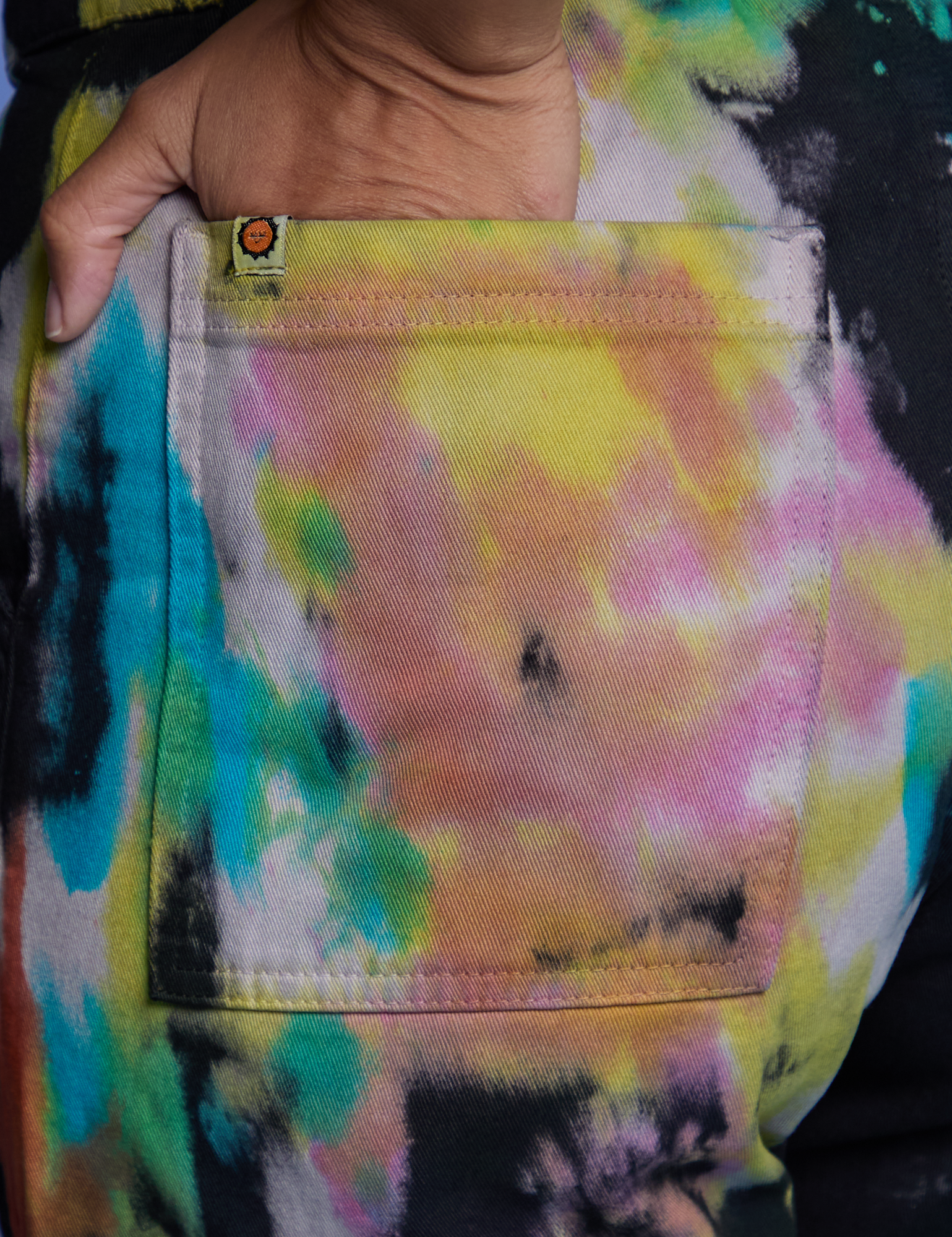 Close up of Tiara&#39;s hand in the back pocket of Work Pants in Rainbow Magic Waters