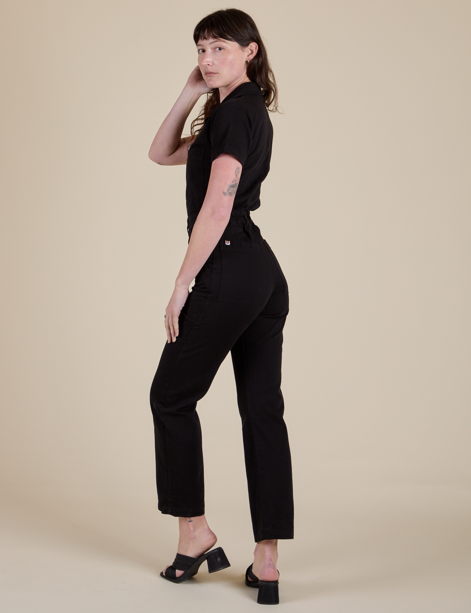 Angled back view of Short Sleeve Jumpsuit in Basic Black on Alex