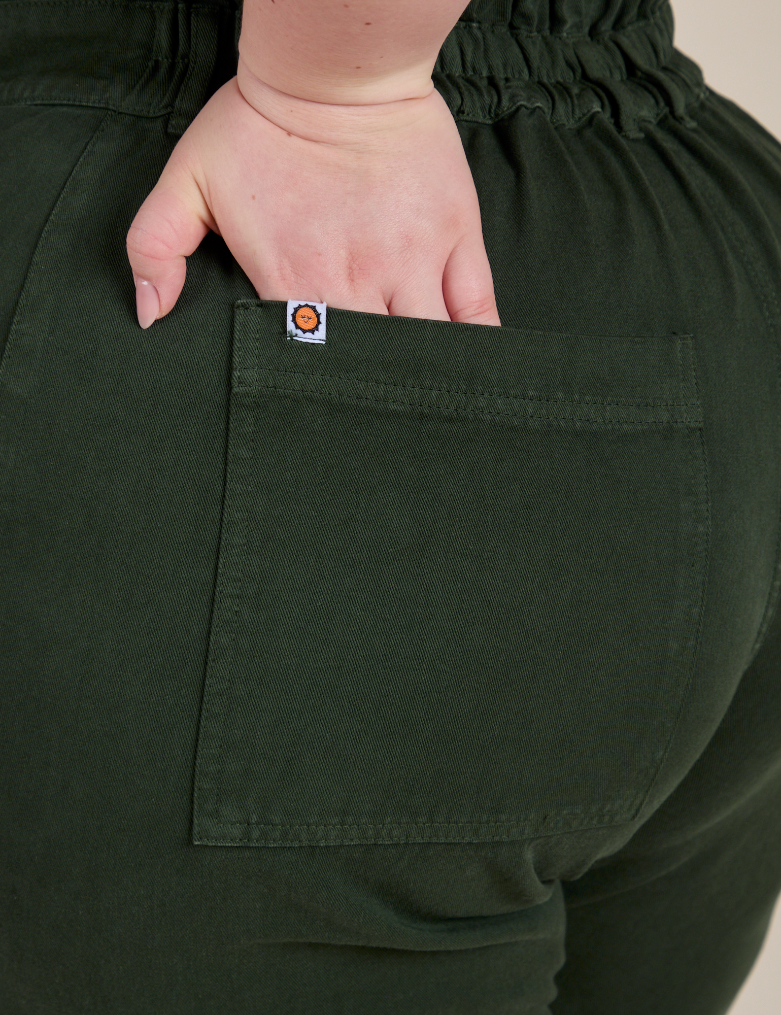 Close up of Ashley's hand in the back pocket of Short Sleeve Jumpsuit in Swamp Green