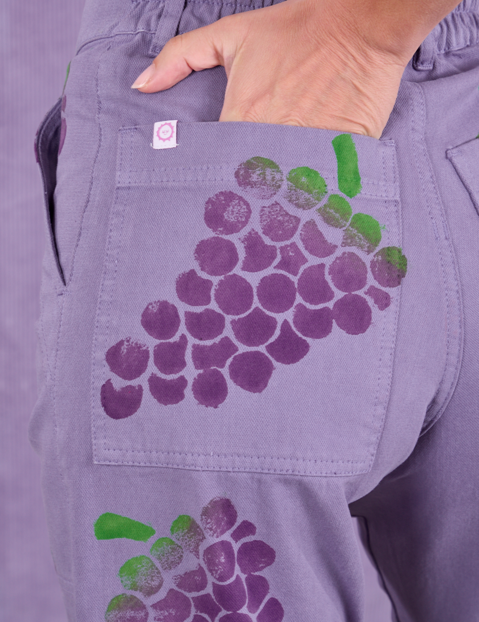 Close up of Madeline&#39;s hand in the back pocket of Paintstamped Work Pants in Grape