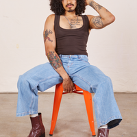 Jesse is wearing Cropped Tank Top in Espresso Brown and light wash Sailor Jeans sitting in an orange stool