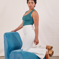 Mika is kneeling on a bright blue upholstered chair wearing Tank Top in Marine Blue and vintage off-white Western Pants