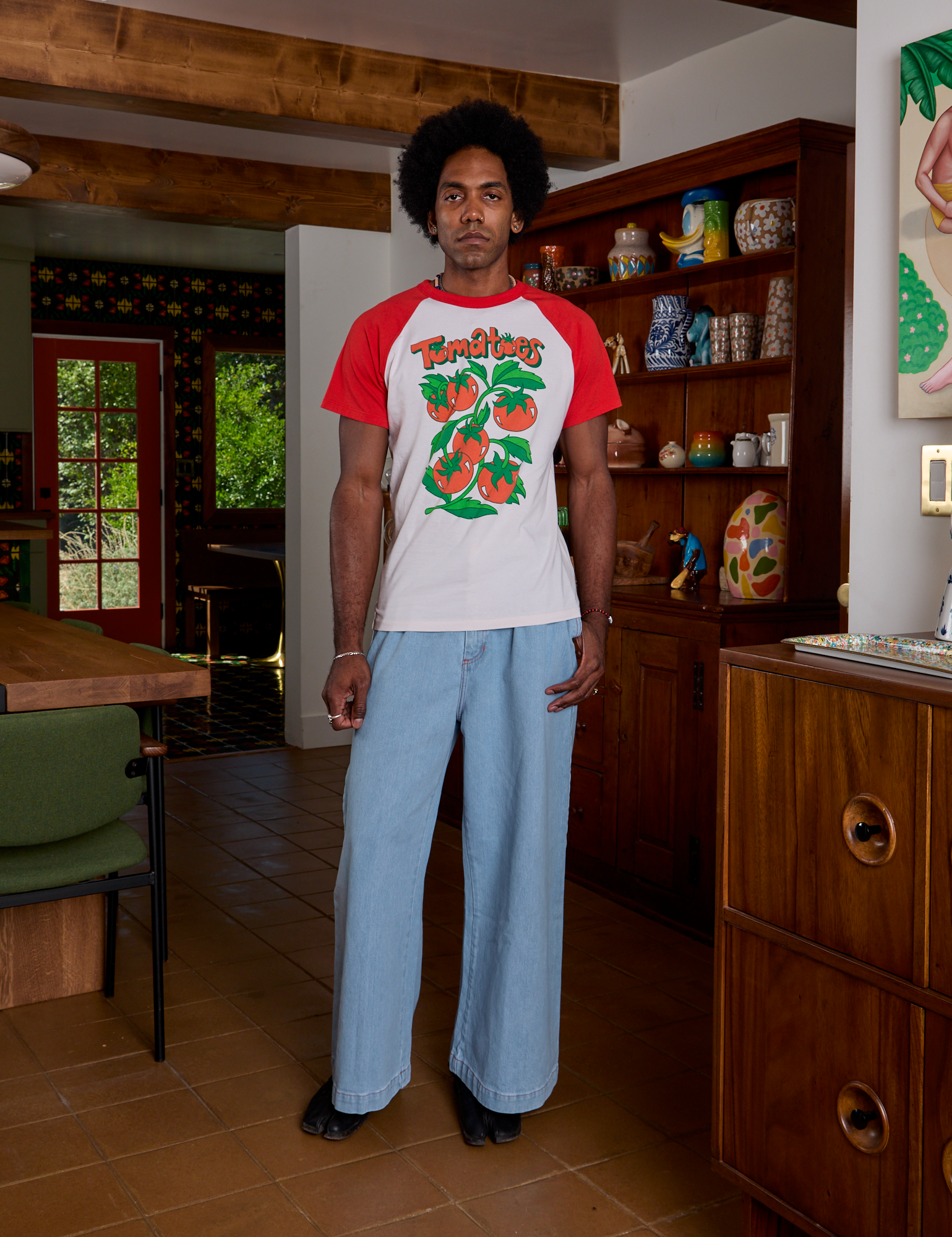 Jerrod is wearing Short Sleeve Raglan Tee in Tomatoes paired with light wash Indigo Wide Leg Trousers