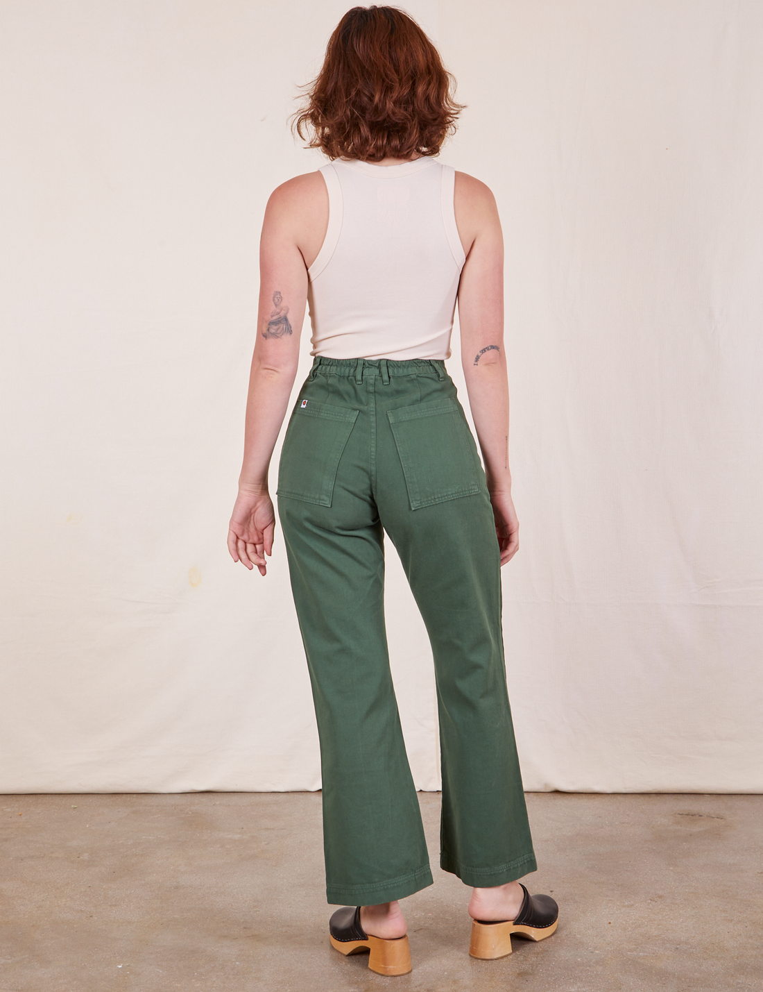 Back view of Western Pants in Dark Green Emerald and vintage off-white Tank Top worn by Alex