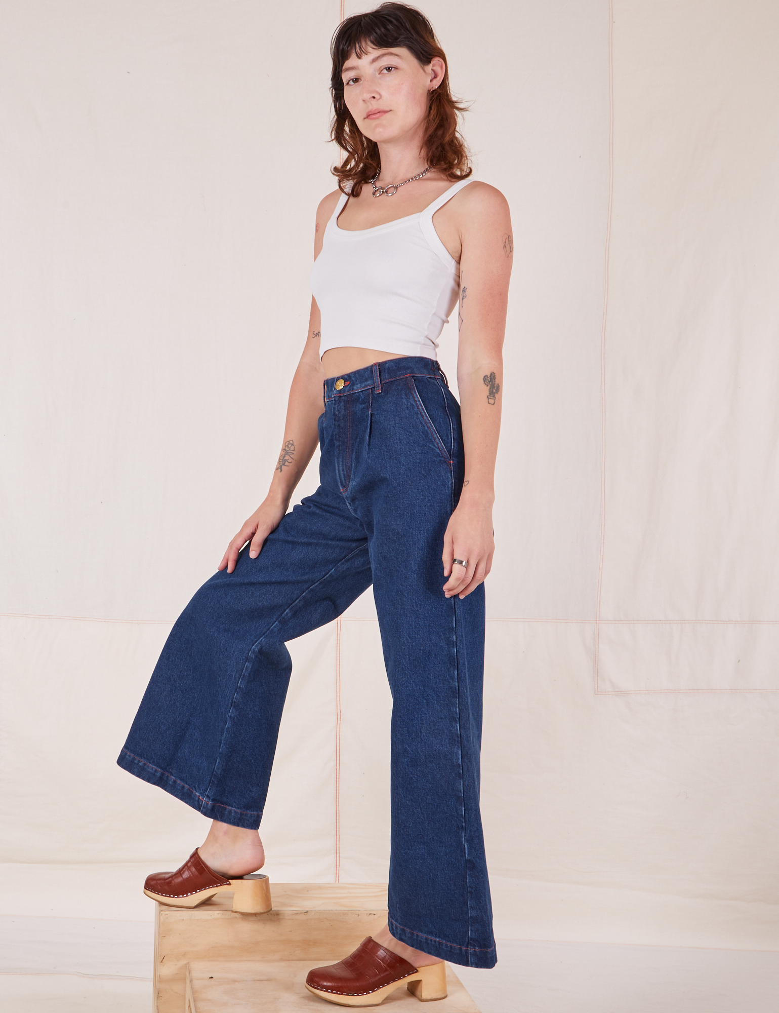 Side view of Indigo Wide Leg Trousers in Dark Wash and vintage off-white Cami on Alex