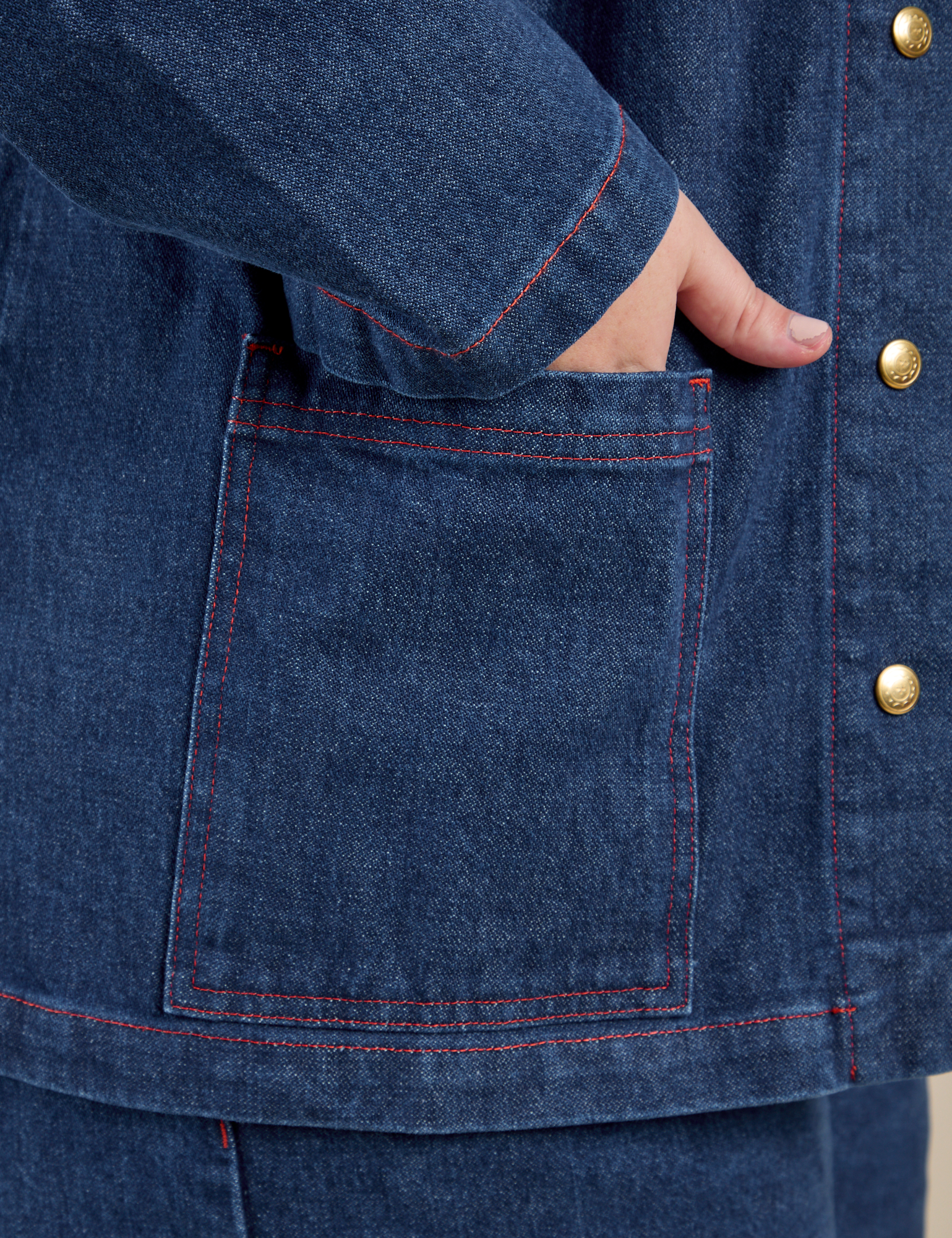 Close up of Juliet's hand in the bottom front pocket of Indigo Denim Work Jacket in Dark Wash