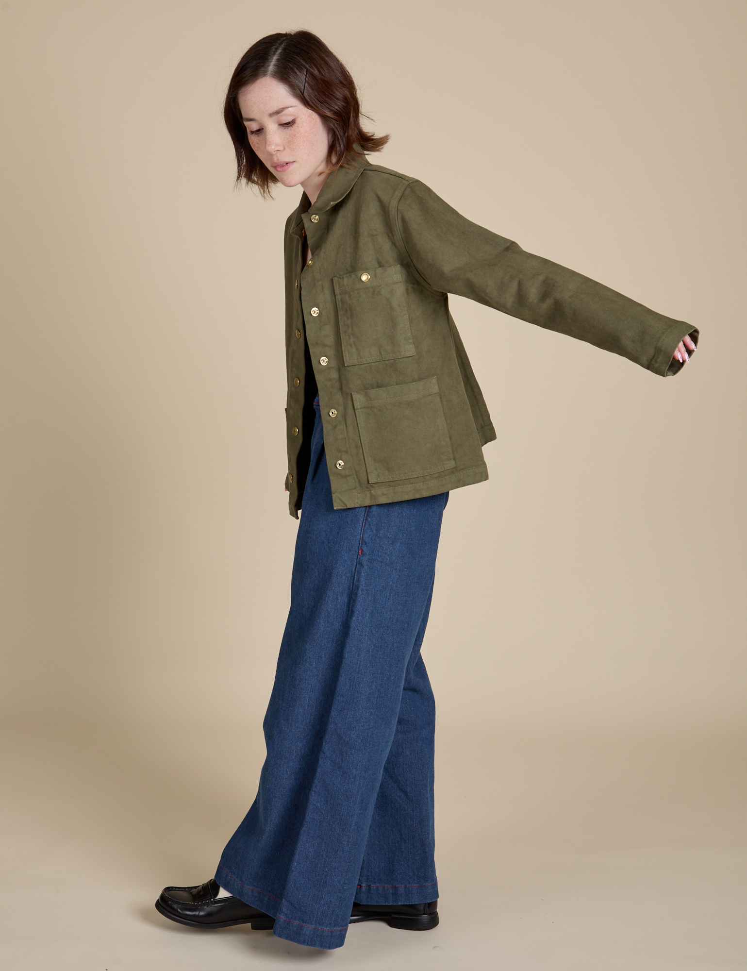 Side view of Denim Work Jacket in Surplus Green and dark wash Wide Leg Trousers on Hana