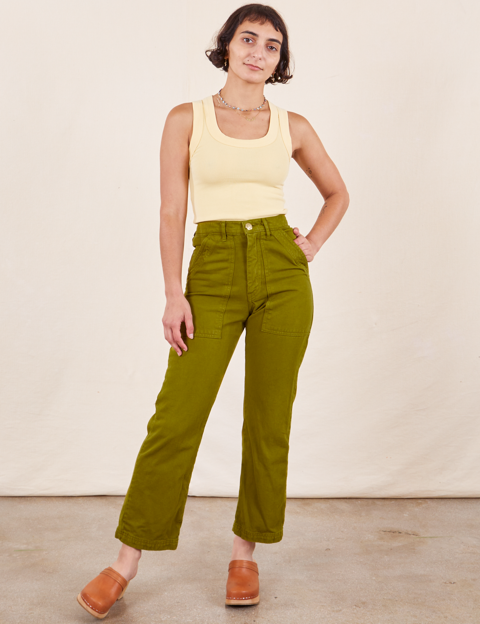 Soraya is 5&#39;2&quot; and wearing Petite XXS Work Pants in Olive Green paired with butter yellow Tank Top