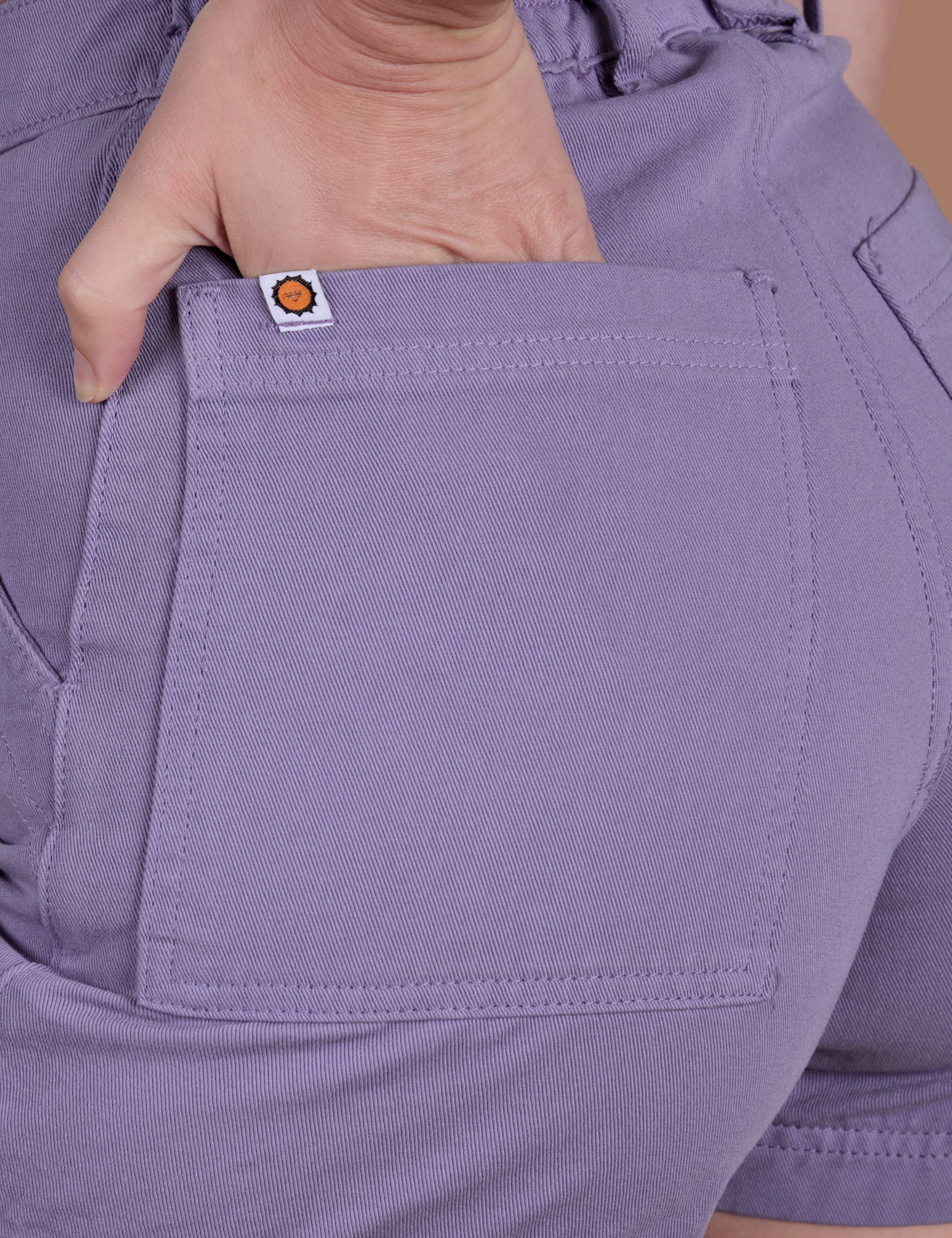Close up of Alex's hand in the back pocket of Classic Work Shorts in Faded Grape