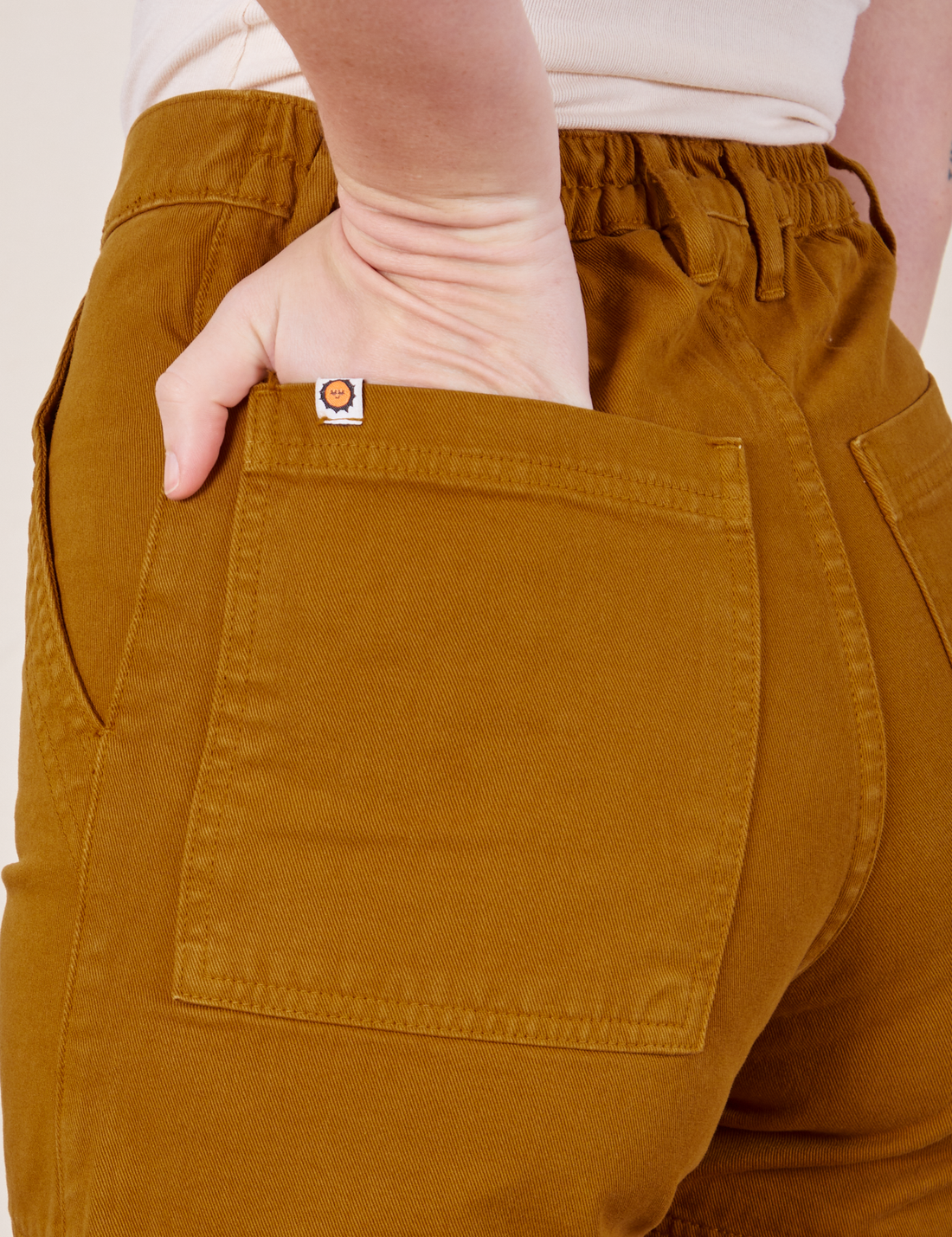 Classic Work Shorts in Spicy Mustard back pocket close up. Alex has her hand in the back pocket.