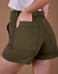 Close up of Alex's hand in the back pocket of Classic Work Shorts in Surplus Green