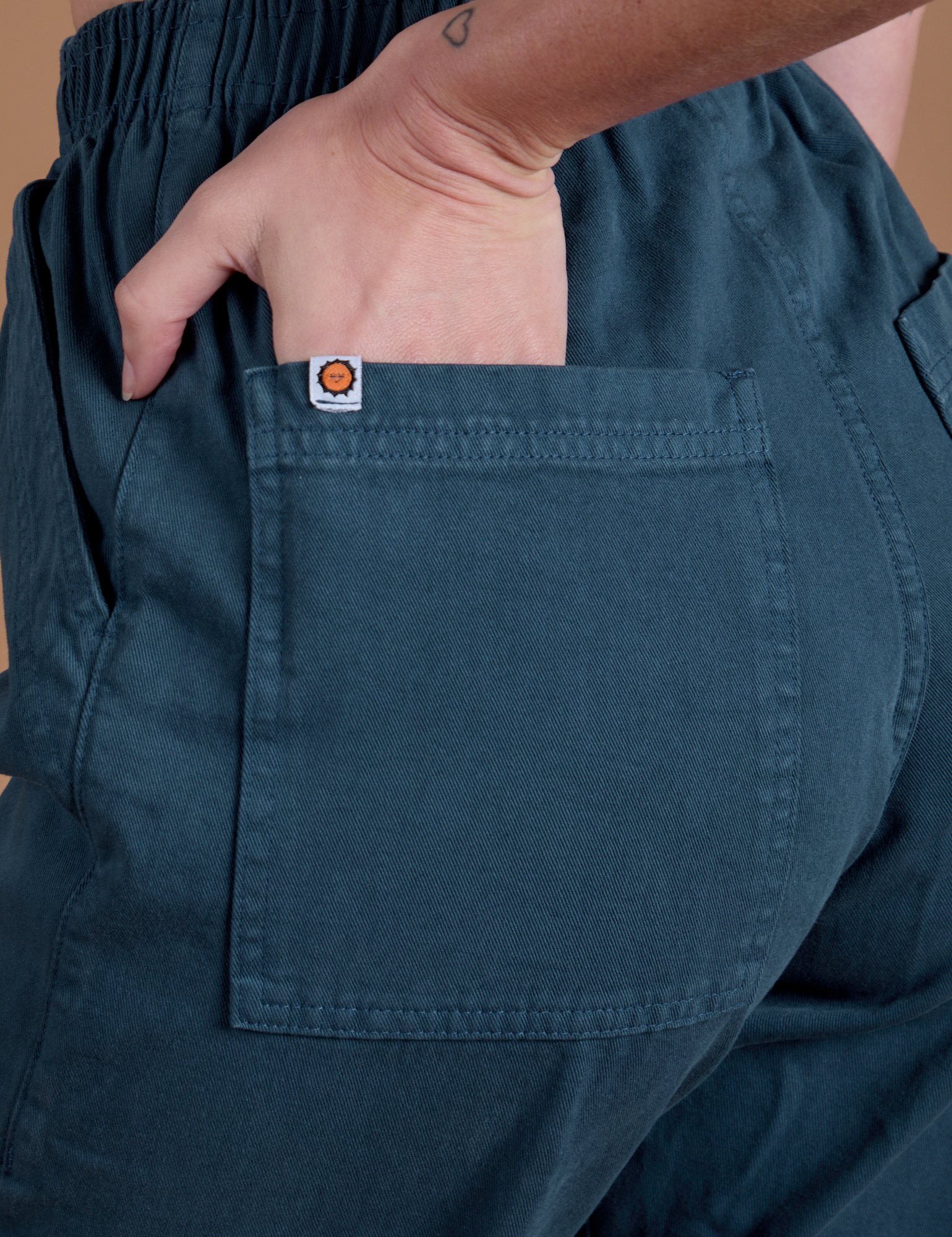 Close up of Alex's hand in the back pocket of Action Pants in Lagoon