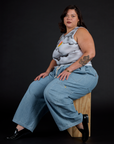 Side view of the Dark Cloud Airbrush Muscle Tee and Light Wash Denim Drop Pocket Cargo Pants worn by Kristen