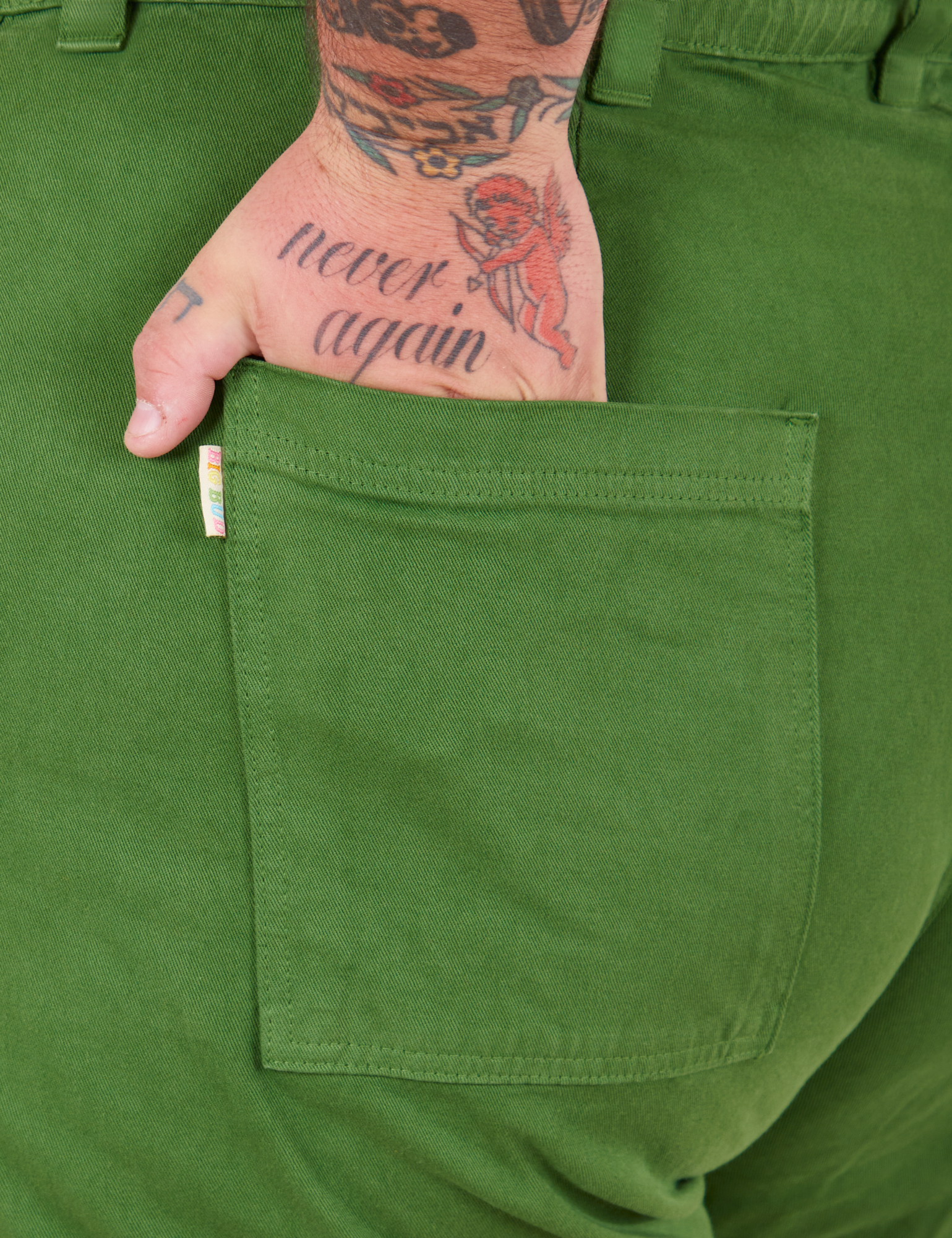 Bell Bottoms in Lawn Green back pocket close up. Sam has their hand in the pocket.