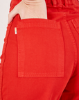 Bell Bottoms in Mustang Red back pocket close up. Alex has her hand in the pocket.