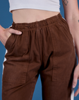 Close up of Alex's hand in the front pocket of Painted Action Pants in Fudgesicle Brown