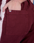 Close up of Alex's hand in the back pocket of Painted Action Pants in Red Wine