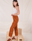 Side view of Carpenter Jeans in Burnt Terracotta and vintage off-white Cropped Cami on Alex