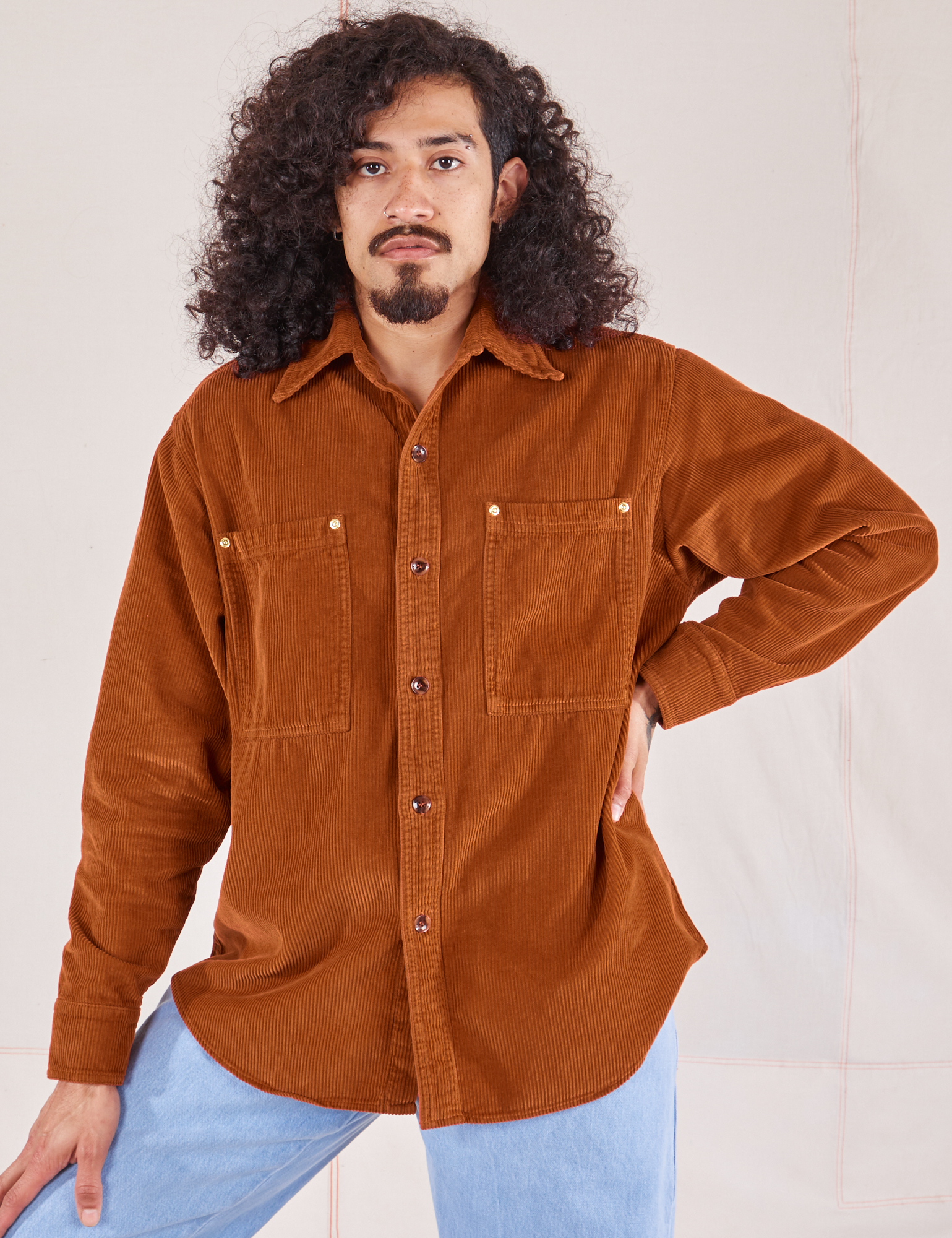 Jesse is wearing a buttoned up Corduroy Overshirt in Burnt Terracotta