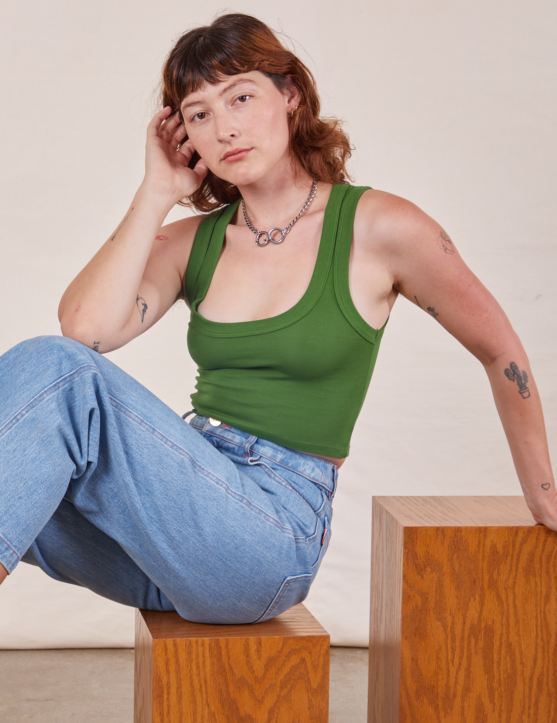 Alex is wearing Cropped Tank Top in Lawn Green and sitting on a wooden box