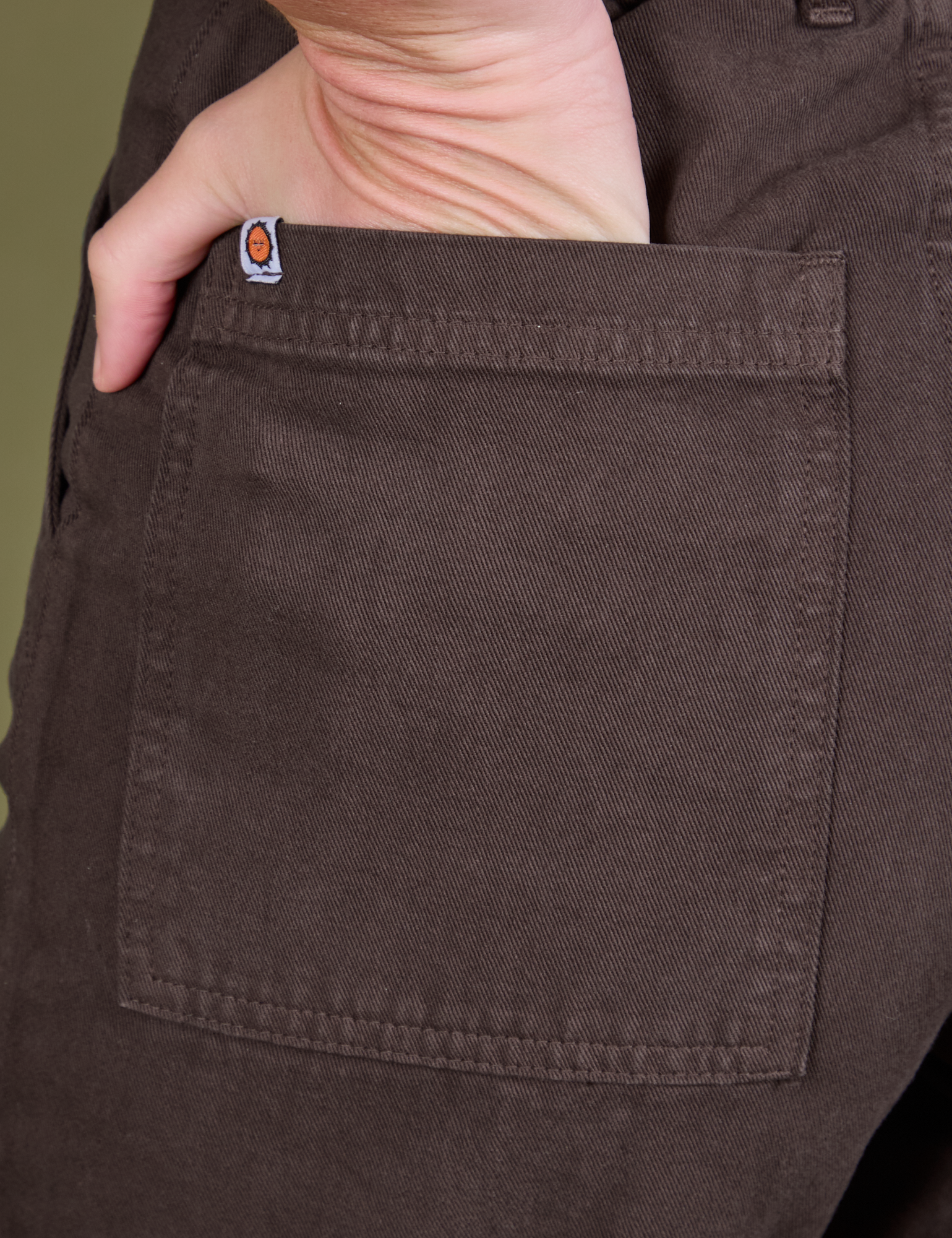 Close up of Alex&#39;s hand in the back pocket of Guy Colwell Work Pants in Woman &amp; Man