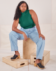 Meghna is wearing Sleeveless Essential Turtleneck in Hunter Green and light wash Denim Trousers