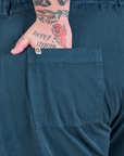 Close up of Sam's hand in the back pocket of Long Jumpsuit in Lagoon