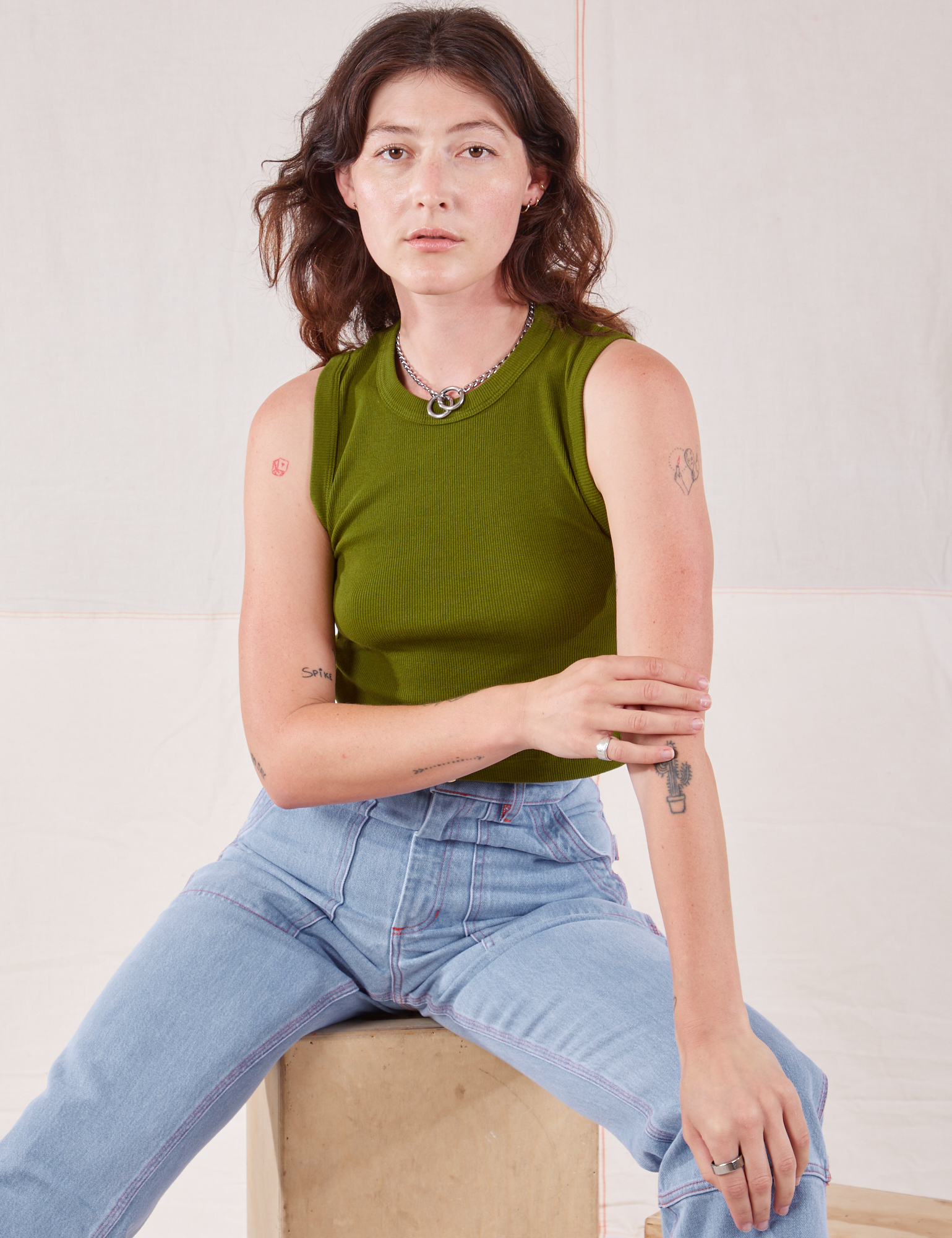 Alex is wearing Muscle Tee in Summer Olive and light wash Carpenter Jeans