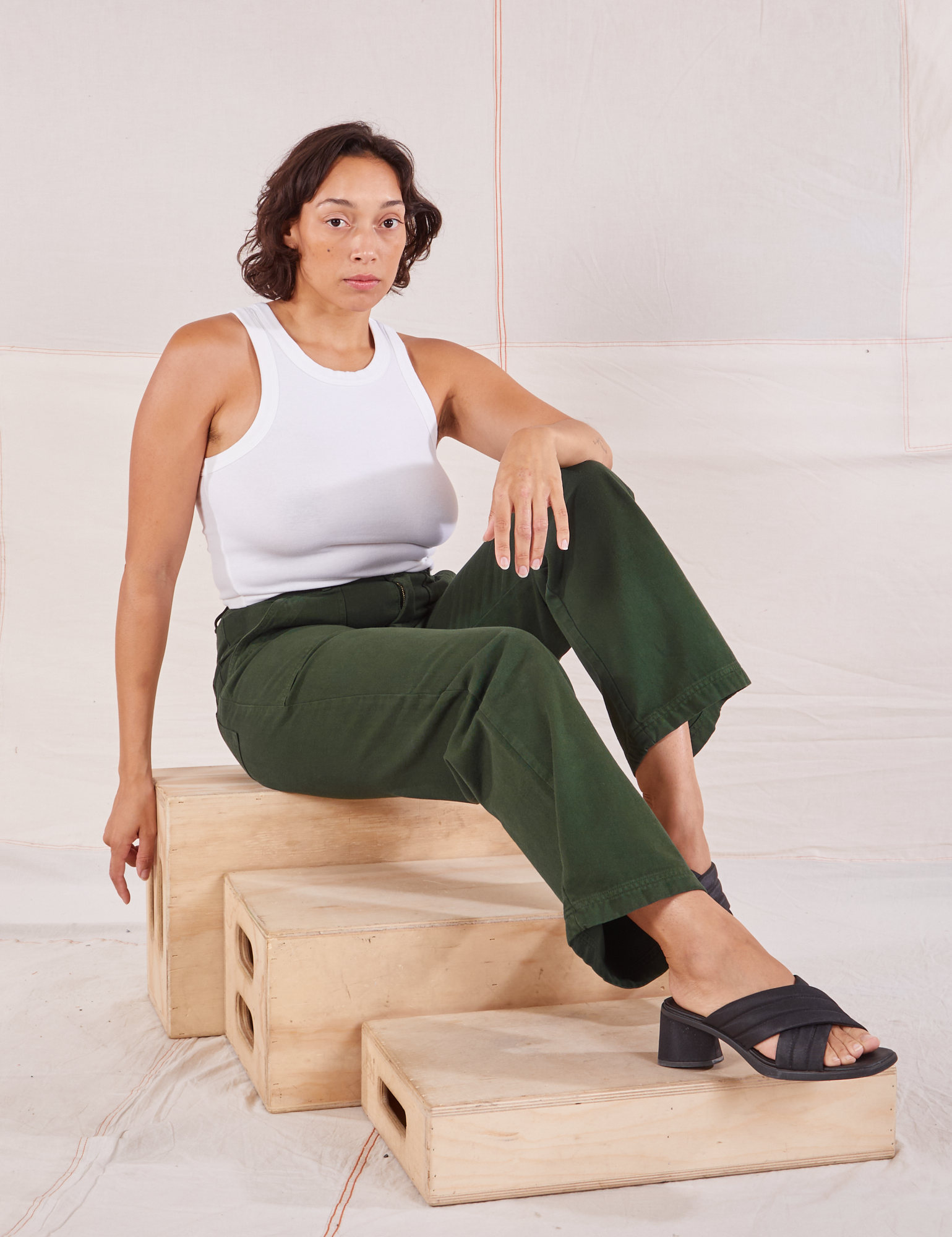 Tiara is wearing Organic Work Pants in Swamp Green and Racerback Tank in vintage tee off-white