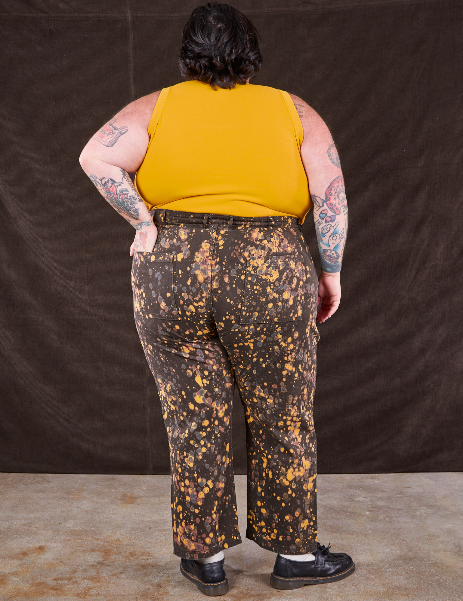 Back view of Marble Splatter Work Pants in Espresso Brown and mustard yellow Tank Top on Sam