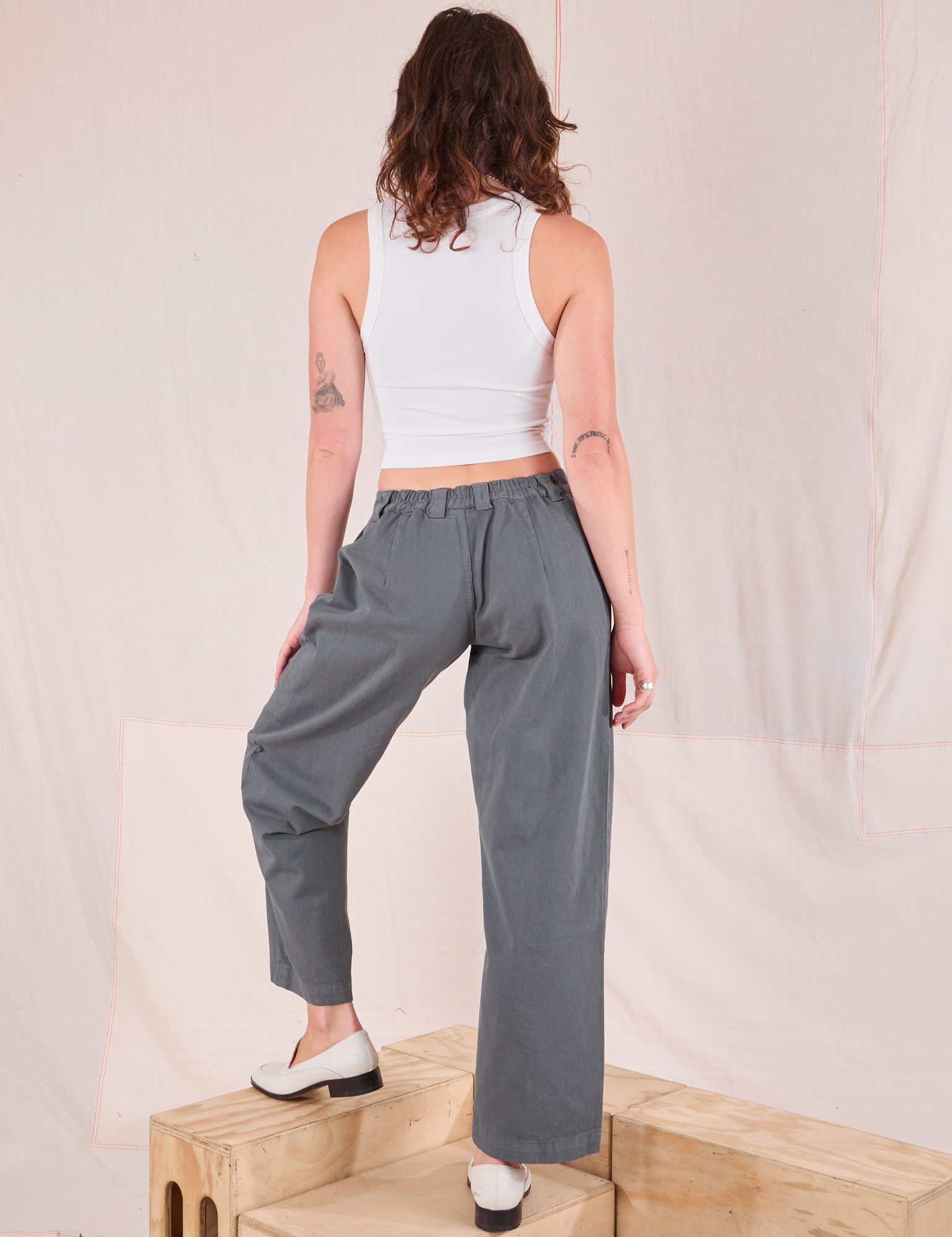 Back view of Mid-Rise Pleated Trousers in Slate Grey and Cropped Tank in vintage tee off-white on Alex